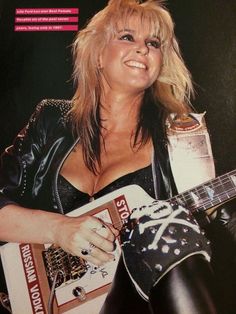 a woman in black leather holding a guitar