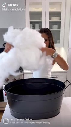 a woman is blowing cotton in a pan