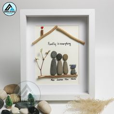 a family is everything framed in a white frame with some rocks on it and a small tree next to it