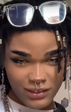 a close up of a person wearing sunglasses and piercings on his nose with chains