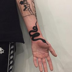 a person with a tattoo on their arm holding onto a hand that has a snake drawn on it