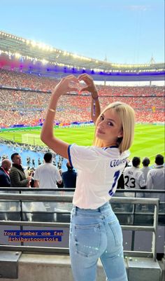 a woman standing in front of a stadium filled with people