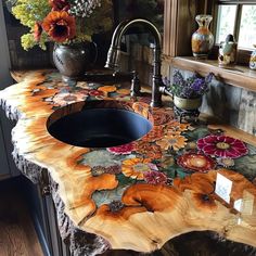 a kitchen counter made out of wood with flowers painted on it and a sink in the middle