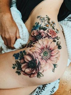 a woman laying on top of a bed covered in blankets next to her stomach with flowers painted on it