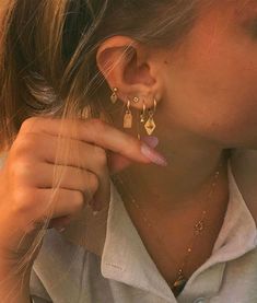 a close up of a person wearing gold earring and necklace with earrings on them