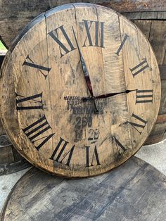 an old wooden clock sitting on top of some stacked wood barrels with roman numerals