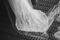 black and white photo of bride's wedding dress on the floor with veil over her head