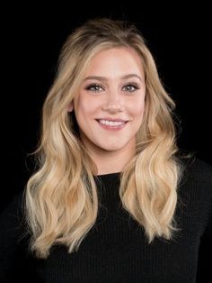 a woman with long blonde hair smiling at the camera