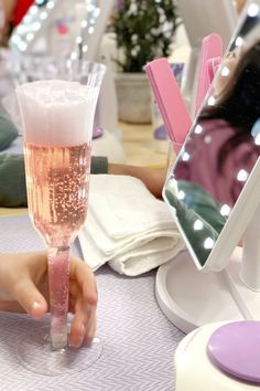 a person holding a wine glass in front of a mirror on a table with other people