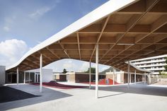 an empty parking lot in front of a building with wooden roof and white columns on the sides