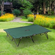 a green table sitting on top of a lush green grass covered field next to yellow flowers