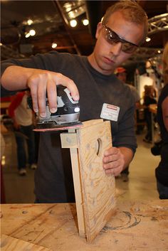 a man working on a piece of wood with a sanding machine in his hand