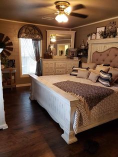 a bedroom with a bed, dressers and fan in it's centerpiece