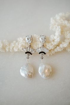 Our BELLE Freshwater Pearl Earrings are so unique and drop dead gorgeous. Made with white cubic zirconia and freshwater pearl, they're made to stand out. They were designed for the classic, yet bohemian chic bride. They add a beautiful touch to every bridal look!---------------------FEATURES◊ White cubic zirconia oval post (.925 sterling post, rhodium or gold plated)◊ Flat freshwater pearl ◊ Cubic zirconia fan pendant (rhodium/gold plated)◊ 100% nickel free, great for sensitive ears--> Get th Silver Art Deco Bridal Earrings With Dangle Shape, Silver Art Deco Dangle Bridal Earrings, Art Deco Silver Dangle Bridal Earrings, Art Deco Dangle Bridal Earrings For Anniversary, Art Deco Bridal Dangle Earrings For Anniversary, Silver Art Deco Drop Bridal Earrings, Art Deco Silver Drop Bridal Earrings, Silver Art Deco Bridal Drop Earrings, Art Deco Wedding Jewelry For Pierced Ears