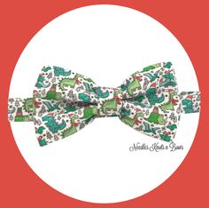 a white bow tie with green and red animals on it, sitting in front of a circle