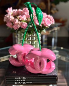 a vase with pink flowers sitting on top of a table next to a stack of books