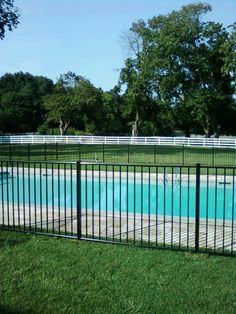 a fenced in swimming pool surrounded by green grass