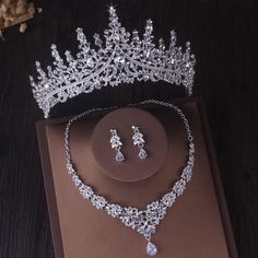 a tiara and earring set on top of a brown box next to flowers