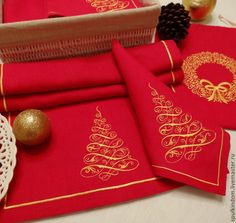 red napkins with gold designs on them sitting next to a basket and pine cones