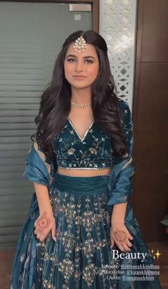 a woman in a blue and gold dress posing for the camera with her hands on her hips