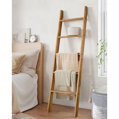 a wooden ladder leaning against the wall next to a bed with blankets and towels on it