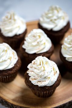 chocolate cupcakes with white frosting on a wooden plate