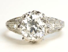 an antique style diamond ring with filigrees on the band and center stone