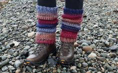 a person standing on top of a rocky ground wearing boots and leg warmers with multicolored stripes