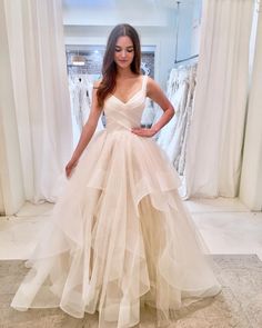 a woman standing in front of a window wearing a dress with ruffles on it