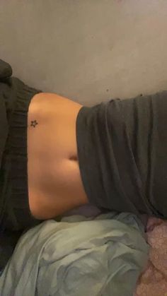 a woman laying on top of a bed with her stomach exposed