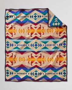 an orange, blue, and yellow blanket on a white surface with geometric designs in the middle