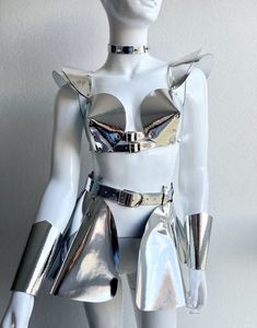 a white mannequin with silver metal accessories on it's chest and arms