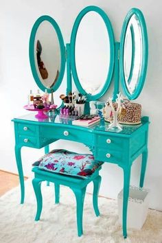 a blue vanity with three mirrors and a stool