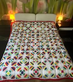 a quilted bedspread with flowers and candles in front of the headboard