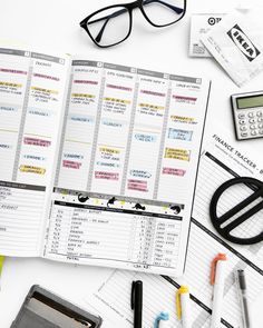 an open planner sitting on top of a desk next to a calculator and pen