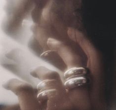 a woman holding her hands up to her face with two rings on it's fingers