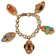 This fanciful vintage creation is uniquely the product of master goldsmiths working in Italy during the Mid-20th Century. Mounted on the very intricate bracelet of the same period are five very detailed and handmade Etruscan Revival charms, each set with numerous precious stones. Included are Mediterranean orange coral, dyed chalcedony, turquoise and Baltic Amber. Average charm length is 1 3/8 inches and bracelet length is 7 1/2 inches. The bracelet and the bale to each individual charm are stamped 750, designating 18k gold. Gross weight 114 grams. Solid Gold Charms, Locket Bracelet, Orange Coral, Gold Charm Bracelet, Locket Charms, Bangle Bracelets With Charms, Body Jewellery, Baltic Amber, Gold Charm