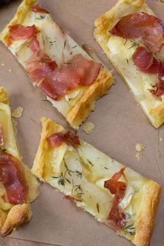 four pieces of pizza with ham and cheese on them sitting on a piece of parchment paper