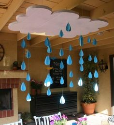 some blue rain drops are hanging from the ceiling in front of a fireplace and potted plant