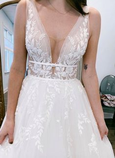 a woman in a wedding dress looking at herself in the mirror with her hands on her hips