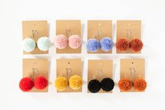 six pairs of pom - pom earrings are shown in different colors and sizes