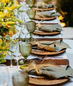 a long table with place settings and flowers on the top, along with napkins