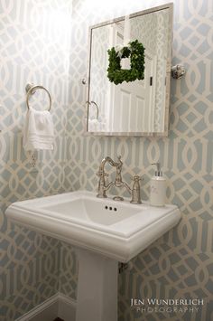 a white sink sitting under a bathroom mirror next to a wall mounted faucet