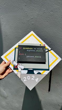 someone is holding up a paper graduation cap