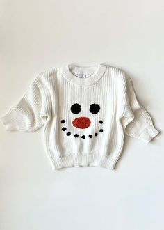 a white sweater with a red nose and black dots on the chest is sitting on a white surface