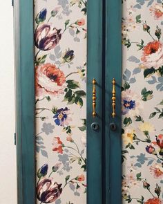 two blue doors with floral wallpaper on them and gold handles in front of each door