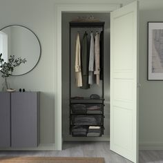 an open closet with clothes on hangers, and a mirror above the door that is next to it