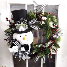 a wreath with a snowman wearing a top hat and bow tie on the front door