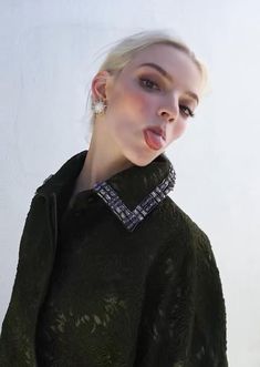 a woman sticking out her tongue while wearing a black top and jacket with an embellished collar