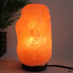 a himalayan salt lamp on a table next to a potted plant